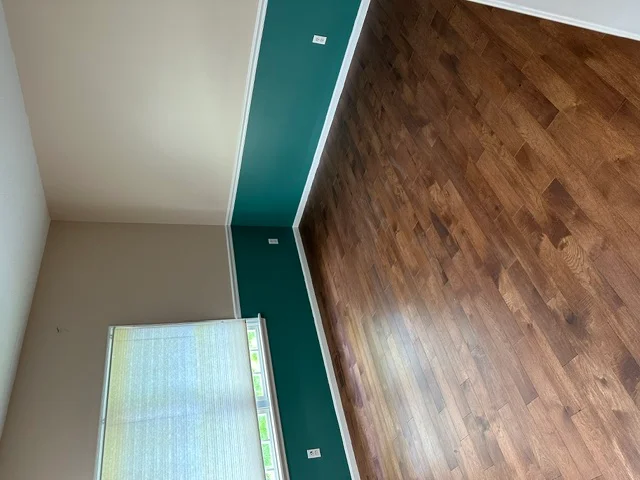 Hardwood flooring installation with teal transition strip and finished walls