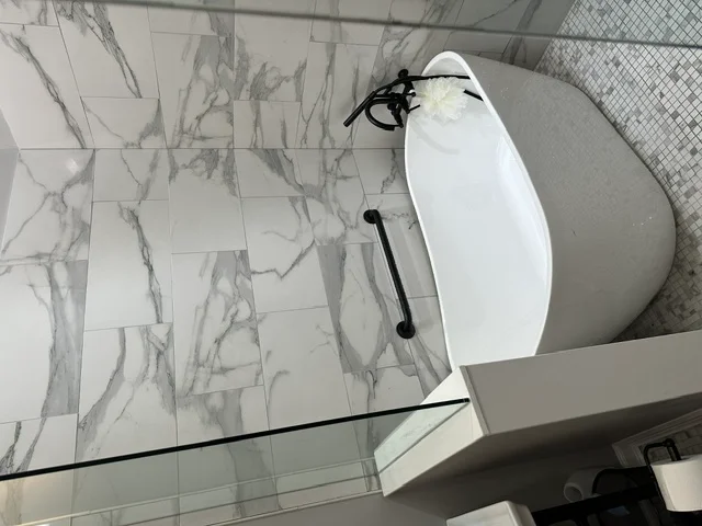 Newly renovated bathroom with marble-pattern tile flooring and white vanity