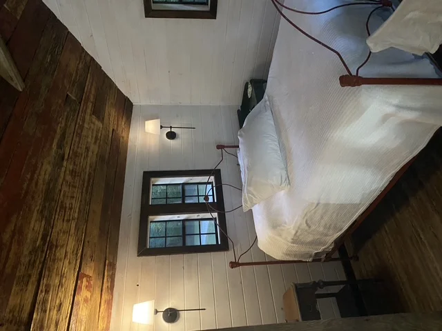 Interior room with hardwood accent wall, white drywall ceiling, and black-framed windows