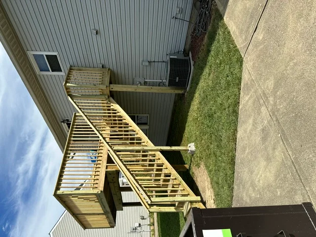 Multi-level pressure-treated wood deck with stairs attached to residential home