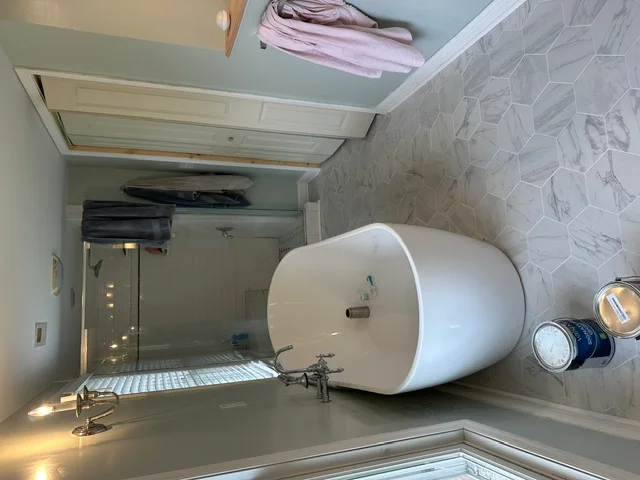 Modern bathroom with white water heater, gray tile accent wall, and updated plumbing fixtures