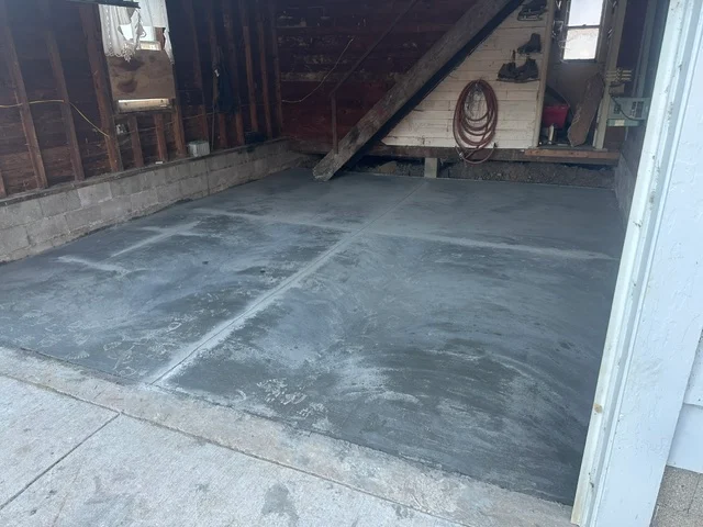 Newly poured concrete garage floor with smooth gray finish and drainage slope