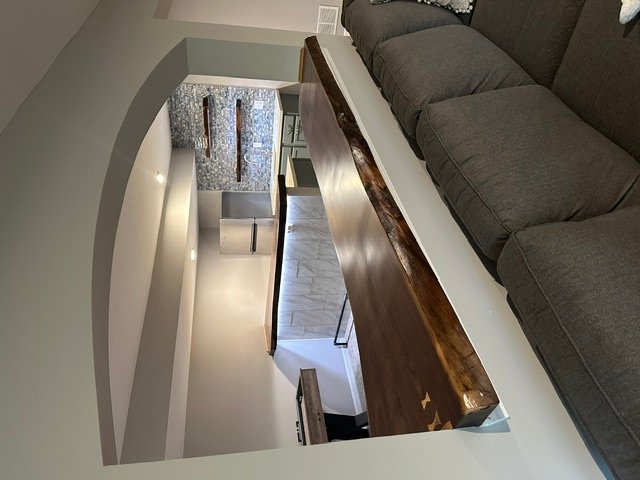 Loft opening with curved drywall archway and wooden staircase installation
