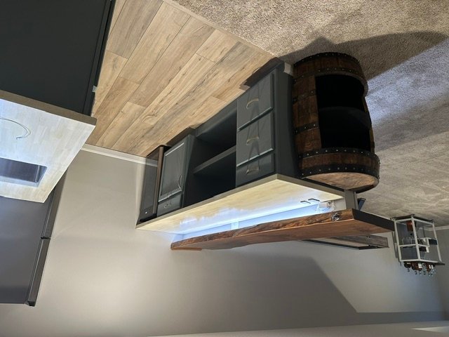 Black glass-front kitchen cabinets with LED lighting and rustic wood floating shelf