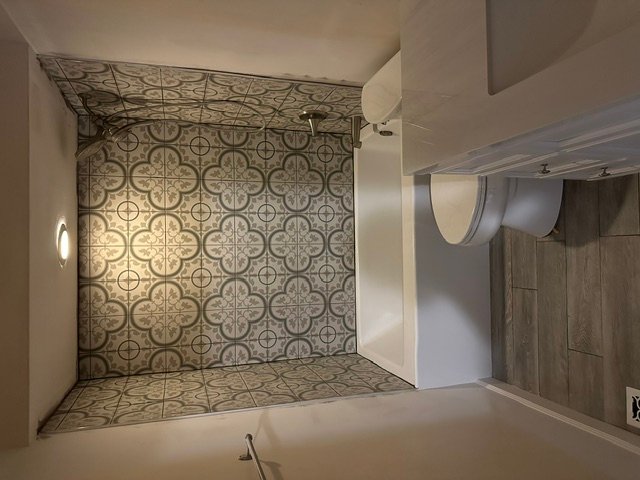 Walk-in shower with geometric patterned tile walls and floor in master bathroom