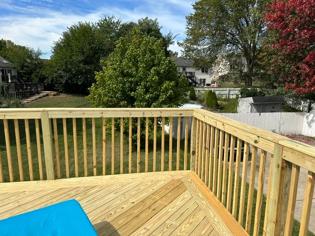 Newly constructed wooden deck with railings overlooking residential backyard
